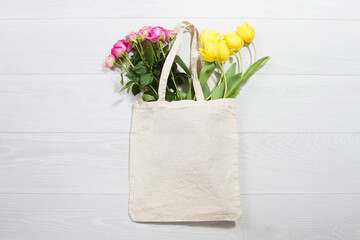 Wall Mural - Mockup shopper handbag. Yellow tulips, pink roses. Wood background. Top view copy space shopping eco reusable bag. Mothers women day. Template blank top view white cotton material canvas cloth.