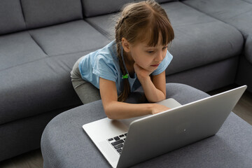 Wall Mural - little girl studying with computer, little girl with laptop online.