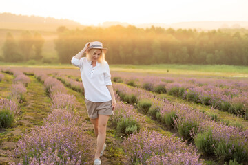 Young woman standing on a lavender field with sunrise on the background