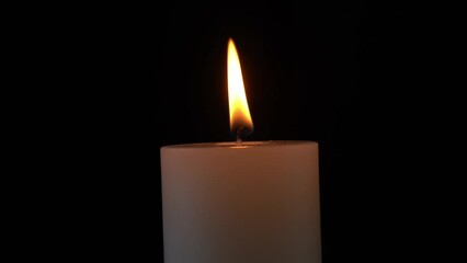 Wall Mural - Closeup of lighted candle on isolated black background