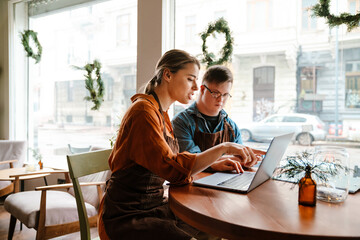 Wall Mural - Woman using laptop while training man with down syndrome to work in cafe