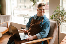 Man With Down Syndrome Using Laptop While Working In Cafe