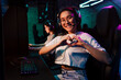 © Drobot Dean - Beautiful asian girl doing heart gesture with fingers while playing online video game in cybersport club