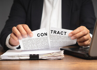 Businessman in a suit tearing up a contract while sitting at the table