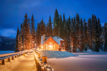 Wall Mural - Emerald Lake with wooden lodge glowing in snowy pine forest on winter at Yoho national park