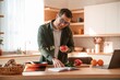 © standret - Reading receipt and holding tomato. Handsome man is on the kitchen at daytime