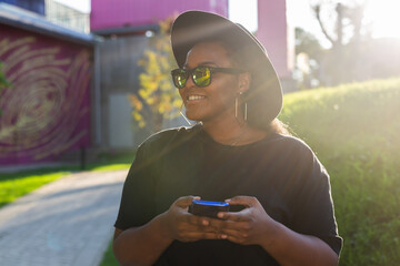 Poster - Close up portrait of happy african american young woman browsing social networks in city - generation z and urban concept