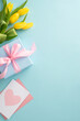 © ActionGP - Mother's day celebration concept. Top view of trendy gift boxes postcard and yellow tulips on pastel blue background with space for text or greeting message
