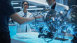 © Gorodenkoff - Diverse Multiethnic Team of Industrial Engineers Gathered Around a Table With a Prototype Turbofan Engine. Scientists Discuss the Futuristic Motor, Use Equipment and Tablet Computer for Research.