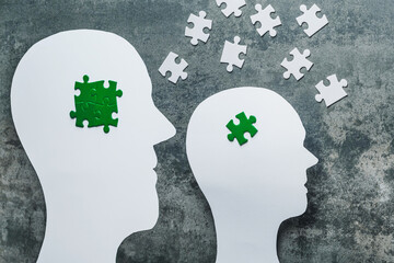 eco-anxiety affecting mental health. paper cuting two heads with green puzzles in concrete backgroun