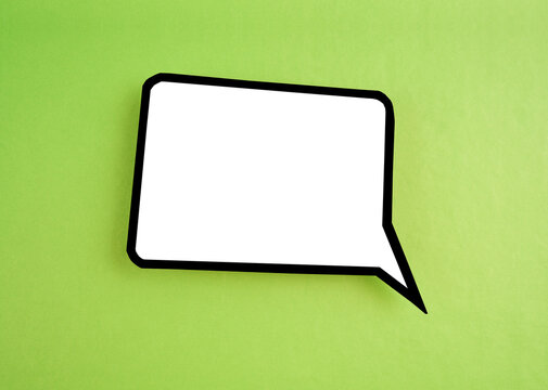 The White speech bubble shaped post it note on green background with copy space.