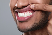Man showing healthy gums on grey background, closeup