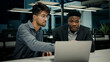 © Yuliia - Businessman african man lawyer mentor help male indian client with computer work consult customer explain online business software services ethnic men colleagues look at laptop screen office meeting