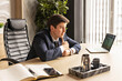 © Светлана  - Tired young man businessman, worker, lawyer at work. He has a headache, keeps his hands on his head, sits at a desk in the office