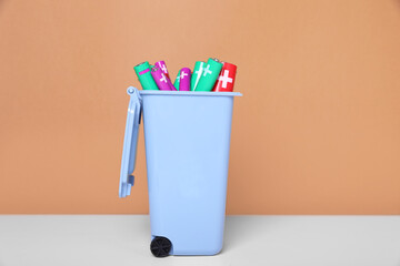 Sticker - Many used batteries in recycling bin on white table against light brown background