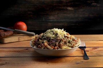 Poster - Tasty Italian pasta penne with tomato and cheese on a wooden table