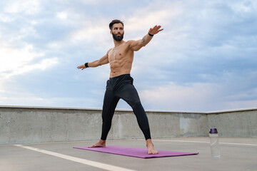 attractive hansome man with athletic strong body doing morning yoga asana outdoors