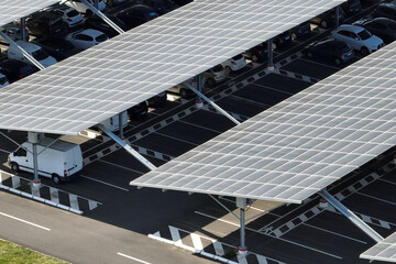 Wall Mural - Aerial view of solar panels installed as shade roof over parking lot with parked cars for effective generation of clean electricity. Photovoltaic technology integrated in urban infrastructure