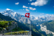 Swiss Flag Flying High Above The Lauterbrunnen Valley On Mannlichen Mountain.