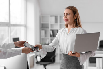 Canvas Print - Female accountant with calculator, laptop and colleague in office