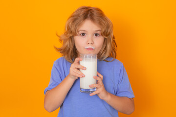 Wall Mural - Little child drinking milk. Kid with glass of milk on yellow isolated background.