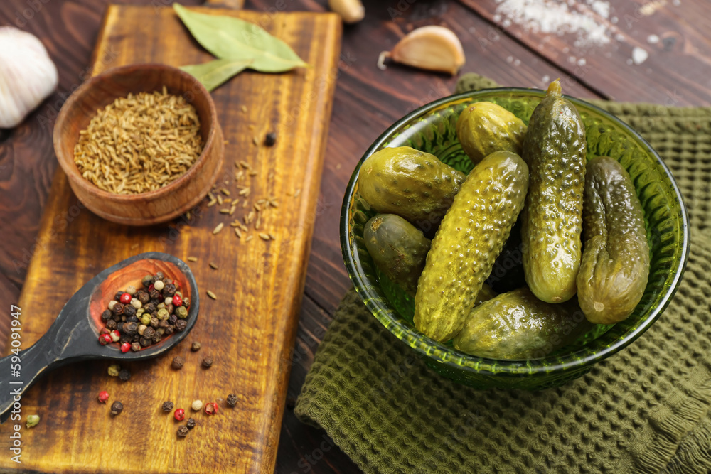 Bowl with tasty fermented cucumbers on wooden background