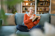 © Miljan Živković - Senior woman mature caucasian female read book at home wear eyeglasses