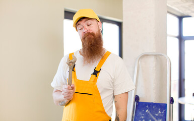 red hair man smiling and looking with a happy confident expression repairing home. handyman concept