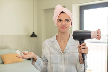 Wall Mural - young pretty woman shrugging, feeling confused and uncertain. hair dryer concept