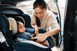 © geargodz - happy mother is fastening safety belt to newborn baby in car seat