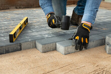 Construction Worker Laying Cement Pavement On A Walkway With Gloves And Rubber Hammer. House Improvement.