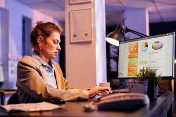 Executive manager analyzing marketing growth report, typing investment strategy on computer trying to increase company profit. Entrepreneur working late at night at research plan in startup office