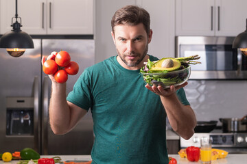 Portrait of handsome man in kitchen. Young man preparing delicious and healthy food in home kitchen. Man with recipe cooking vegetable salad in kitchen. Food vegetables ready to cook. Healthy food.