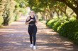 Music, fitness or woman running in park training, cardio exercise or full body workout for marathon. Sports, runner or healthy girl athlete exercising on jog streaming audio or radio song in nature