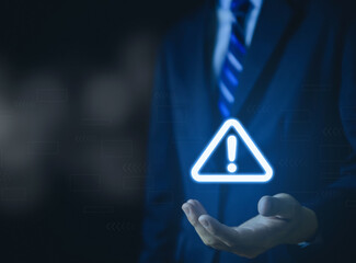 Wall Mural - businessman hand showing warning triangle and exclamation sign icon caution of dangerous problems se