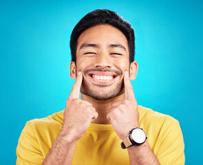 Sticker - Teeth, smile and pointing with a man on a blue background in studio for dental care or oral hygiene. Portrait, face and happy with a handsome young male at the dentist for tooth care or whitening