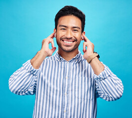 Poster - Portrait, earphones and happy man with music in studio, relax and smile on blue background. Radio, face and asian male listening to podcast, streaming or audio, online or subscription while isolated