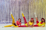 Three stylish young girls in colorful sportswear, bodysuits and leggings training, doing stretching and aerobics exercises. Concept of retro fitness, sport, 80s fashion, beauty, health