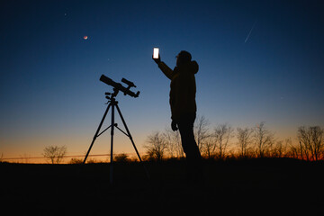 Wall Mural - astronomer looking at the starry skies with planets, falling stars and moon eclipse with a telescope