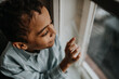 © Halfpoint - Little multiracial boy looking out of window.