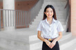 © nut_foto - Beautiful Asian young woman student in Thai student uniform is stand under the school building smiling and looking at camera in university background.