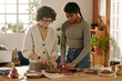 © pressmaster - Mom preparing breakfast together with her daughter in the kitchen, they cutting fresh vegetables for sandwiches