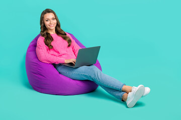 Poster - Full length photo of pretty cheerful lady dressed knitted pullover sitting bean bag typing gadget empty space isolated teal color background