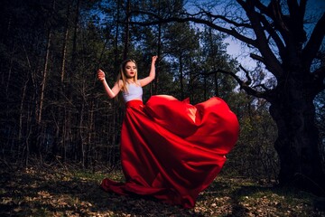 Wall Mural - Fashionable young woman in a red dress a forest