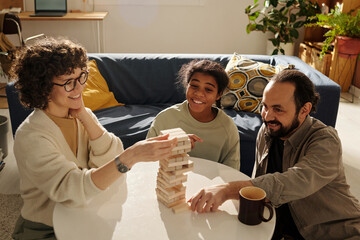 Wall Mural - Happy family playing board game together with adopted child while sitting in the living room at home