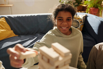 Wall Mural - African AMerican teenage girl playing board game during her leisure time at home