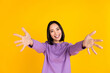 Photo of young japanese woman wear purple shirt friendly want cuddles with you welcome company isolated on yellow color background