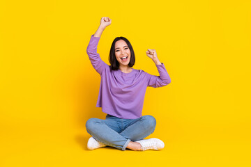 Canvas Print - Photo of funny lucky lady dressed purple shirt sitting floor legs crossed rising fists isolated yellow color background