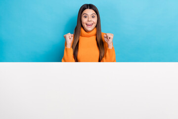 Sticker - Portrait of delighted girl raise fists success luck empty space placard isolated on blue color background