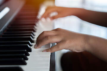 Hands of the child on the piano keys. Selective focus. Music abilities for kids.
